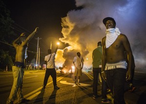 Demonstrators stand in the middle of West Florissant as they react to tear gas fired by police during ongoing protests in reaction to the shooting of Brown, in Ferguson
