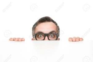 19425257-Funny-nerd-peeking-from-behind-the-desk-isolated-on-white-background-with-copy-space-Stock-Photo